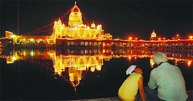 Sikh devotees in front of the illuminated Gurdwara Bangla Sahib on the eve of Guru Nanak Birthday in New Delhi on Wednesday. 