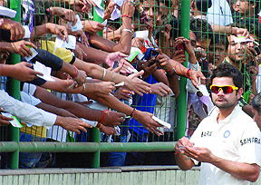 Cricketer Virat Kohli signs autographs during the fourth day of the first cricket Test match between India and the West Indies
