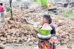 A woman carries her utensils after the MC removed encroachments from the Model Town Extension area in Ludhiana on Wednesday. 