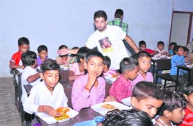 Volunteers of Remove Hunger feed children during project Udaan at a Panipat-based school