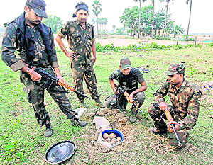 RAF personnel look at a drum packed with bombs on the bank of a pond outside Suchpur village in West Bengals Birbhum district on Sunday. More than 800 bombs and other explosives were seized during a search operation.