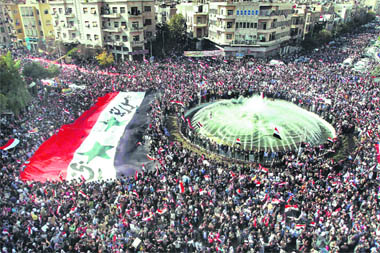 Pro-Syrian regime protesters carry a giant Syrian flag during a demonstration against the Arab League decision to suspend Syria, in Damascus, on Sunday. 