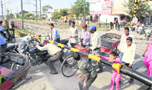Commuters cross the railway crossing from underneath the barriers near Guru Nanak Pura after the rally on Monday.