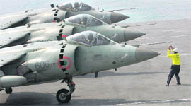 A flight deck officer signals to pilots of Sea Harrier aircraft to take off from the Navys aircraft carrier INS Viraat during an operational demonstration leading to the Presidents Fleet Review off Mumbai coast 