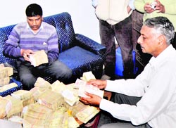 Vigilance officials count the money found in the locker of a former Drug Controller of Uttarakhand in Dehradun on Tuesday