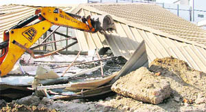 A JCB razes an illegal structure near Ansal Plaza in Ludhiana on Tuesday. 