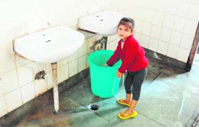A child takes water from a bucket put near the wash basins without taps at Civil Hospital in Amritsar