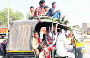 Unaware of the risk involved, passengers sit on the top of a three-wheeler on the Mewat-Gurgaon road.