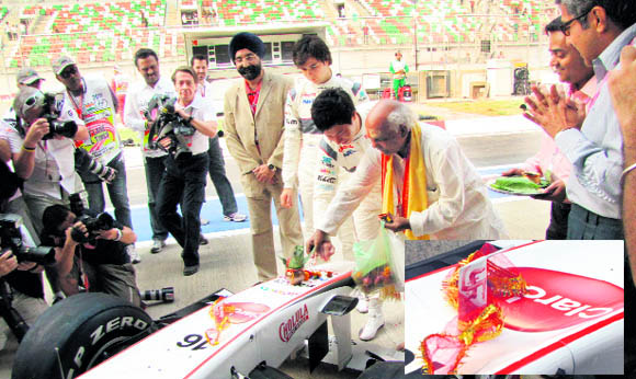 A pandit drawing the swastik on the Sauber Ferrari; (inset) A close-up of the swastik sign.