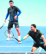 Leander Paes (L) watches as his partner Mahesh Bhupathi returns against Robert Lindstedt of Sweden and Horia Tecau of Romania in the ATP World Tour Finals in London