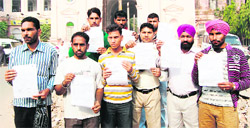 The youths, who were duped by a travel agency, show fake contracts and visa documents outside the Kotwali police station in Amritsar