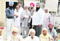 An official hands over a cheque to the family members of one of the beneficiaries of Shagun Scheme in Jagraon on Wednesday. A