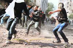SECOND REVOLUTION? Protesters throw stones during clashes with the police along a road leading to the Interior Ministry near Tahrir Square