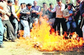BTC trained teachers burn an effigy of state Cabinet minister Matbar Singh Kandari in Dehradun on Saturday