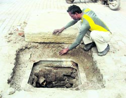 An MC employee covers the open manhole with a slab at College Road, Jagraon, on Sunday