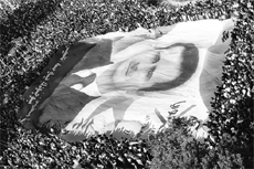 A giant portrait of embattled Syrian President Bashar al-Assad is carried by thousands of Syrian demonstrators in Damascus on Monday. 