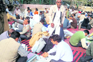 Polling officials wait for vehicles after collecting the EVMs and other material in Ratia on Tuesday. 
