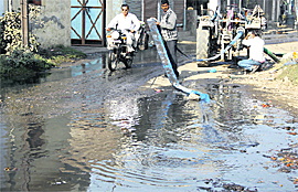 MC employees throw sewage water on the Gujja Peer road after pumping it out from a sewer