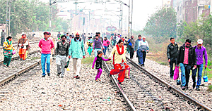Passengers walk on rail tracks after a train was stopped by BJP activists protesting against FDI in the retail sector in Amritsar