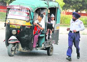 A traffic police personnel tries to catch an overloaded auto-rickshaw in Jalandhar