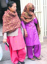 Pooja (face covered with shawl), who had allegedly strangled her two children to death, in police custody in Jalandhar on Thursday
