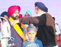 Chief Minister Parkash Singh Badal offers a siropa to Satinderjit Singh, alias Manta, at Roranwali village in Muktsar