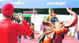 Children pose for a photograph while sitting on a statue of an elephant at PITEX in Amritsar on Sunday.