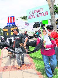 Protesters pull a giant octopus puppet with a hat in the colours of the US flag at a rally in Durban