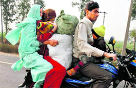 A family, along with its belongings, travels on a motorcycle on the Gurgaon-Alwar road on a winter afternoon.