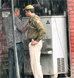 A cop looks on as a youth is seen interacting with an undertrial at the rear of a lockup in Mohali district courts on Tuesday