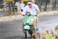 Scooterists try to save themselves from drizzle, which caught residents unaware, in Ludhiana