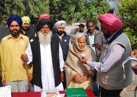 Lieutenant-Colonel (Retd) SS Mann, Deputy Director, Sainik Welfare, presents a paper flag to Dalip Kaur, widow of Lance Dafadar Karnail Singh, on the occasion of the Armed Forces Flag Day in Bathinda on Wednesday