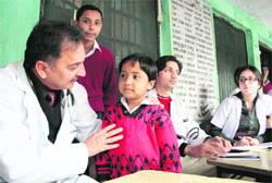 A doctor examines a child at a medical camp at Ghass Mandi School in Jammu on Wednesday.
