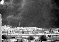 A thick plume of smoke emanates from an oil refinery, situated to the west of Homs, on Thursday