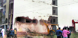 A JCB machine demolishes a five-storeyed building in New Palam Vihar, Gurgaon, on Friday.