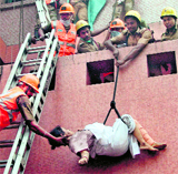 Rescue workers bring down a patient from AMRI Hospital on Friday; grieving relatives of a victim.