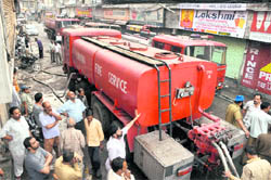 Old fire-tenders douse fire at Books Market; and (right) a fireman uses the shoulder of his colleague to scale a wall during a fire-fighting operation in Ludhiana. 