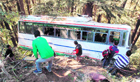 Onlookers gather near the ill-fated private bus that met with an accident at Kanlog in Shimla on Tuesday.