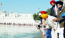 Tourism Minister Hira Singh Gabria (yellow turban) pays obeissance at Amrit Sarovar in Golden Temple.