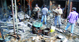 Workers try to recover goods from the godown which was gutted in a fire in Amritsar on Thursday.