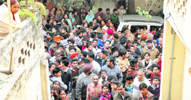 Residents gather outside the house where the double murder was committed.