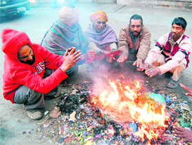 People sit around a bonfire on a chilly day in Amritsar on Saturday. 