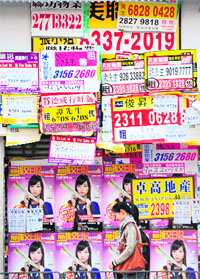 A pedestrian walks past real estate advertisements outside a vacant outlet in Hong Kong on Saturday. Hong Kong has overtaken the United States and Britain to rank top in a World Economic Forum survey on countries' financial health published on December 13