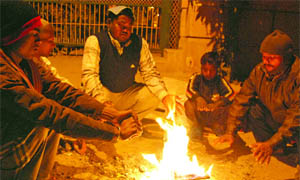 People warm themselves around a bonfire on the roadside as the temperature dips in the Capital on Saturday. 