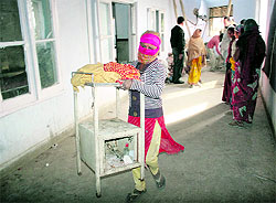 An employee of the Government SMGS Hospital in Jammu tries to salvage furniture on Saturday
