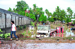 A resident walks past vehicles submerged in floodwaters after tropical storm Washi raged through southern Philippines on Saturday