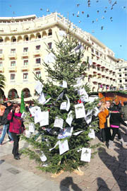Members of the I won't pay movement protest decorate a Christmas tree with power bills including the new emergency property tax in Thessaloniki on Sunday. Greece holds tightrope talks with its international creditors and private debt holders on the application of a new eurozone bailout designed to alleviate its huge loan repayments