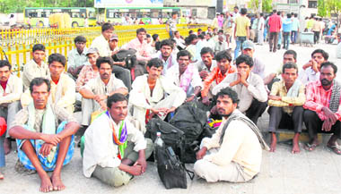 Migrant labourers, who come in search of work, sit outside the railway station.