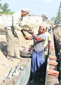 Migrant labourers busy in construction work in Jalandhar.