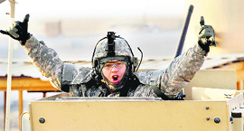 A soldier gestures from the turret of the last vehicle in a convoy of the US Armys 3rd Brigade as it crosses the border from Iraq into Kuwait on Sunday. 